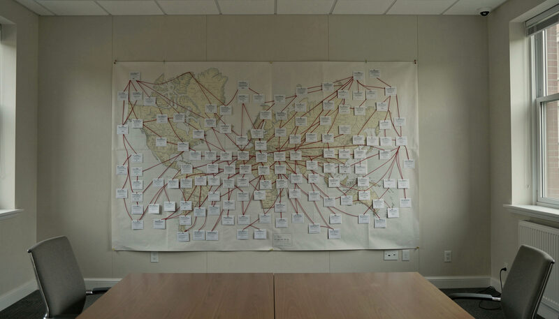 A nonprofit developer's conference table covered with a financing stack: a printed pro forma, a tax credit allocation letter, a bank term sheet and a site plan, lit by late afternoon window light from a Washington DC street, shot at a slight angle from above.